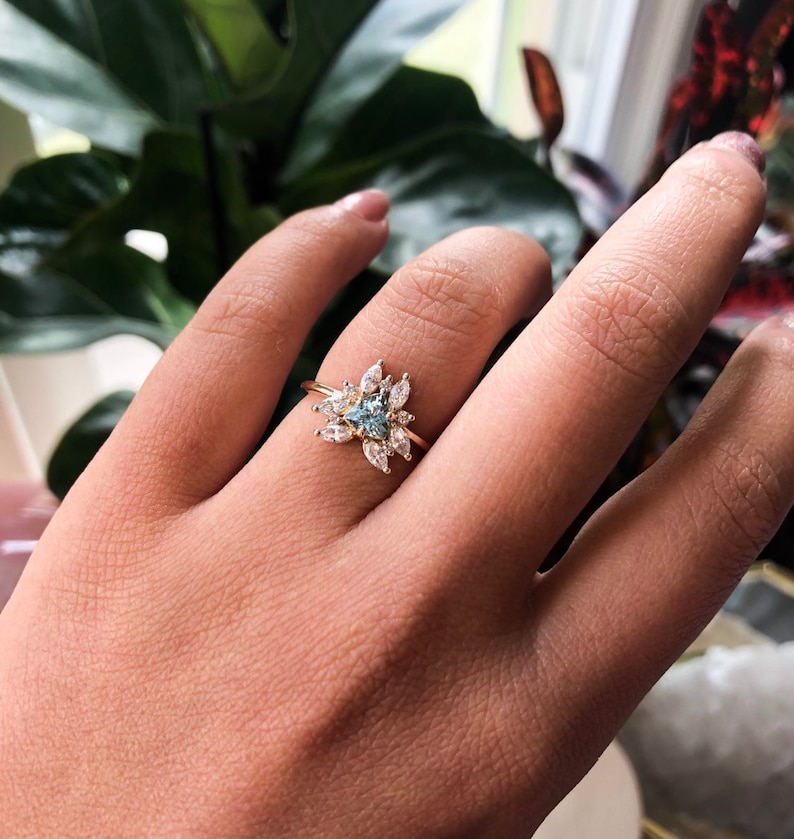 May include: A gold ring with a blue gemstone surrounded by smaller clear gemstones.