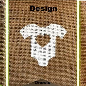 May include: Three burlap banners with white designs and green borders. The banners feature a stork carrying a baby, a onesie with a heart cutout, and a heart shape. The word "Design" is above the onesie.