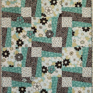May include: A quilt with a patchwork design featuring brown, white, and teal fabric. The fabric has a floral pattern with white flowers and brown centers.