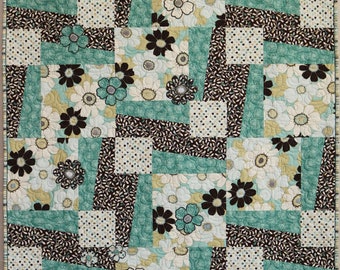 May include: A quilt with a patchwork design featuring brown, white, and teal fabric. The fabric has a floral pattern with white flowers and brown centers.