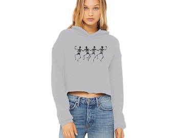 May include: A gray cropped hoodie with long sleeves and a drawstring hood. The hoodie features a graphic of five skeletons dancing in a line.