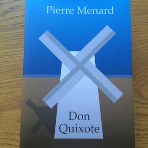 Puede incluir: Una portada de libro con el texto Pierre Menard y Don Quixote. El diseño muestra una silueta de molino de viento blanca estilizada con aspas grises sobre un cielo azul y suelo marrón, con una sombra oscura proyectada a la izquierda.