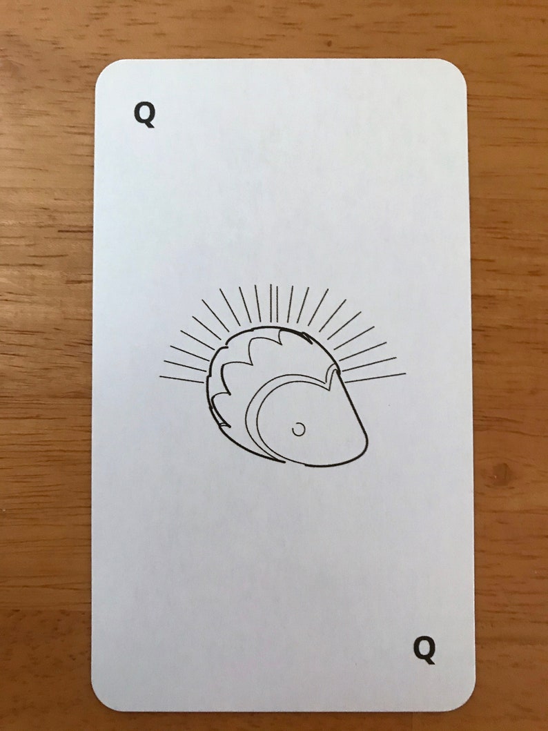 Puede incluir: Una carta de juego rectangular blanca con esquinas redondeadas que presenta un dibujo de l&iacute;nea negra de un erizo en el centro. La letra Q est&aacute; impresa en negro en las esquinas superior izquierda e inferior derecha de la carta.