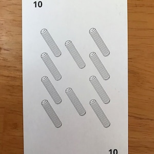 Puede incluir: Una carta de juego rectangular blanca con el n&uacute;mero 10 en las esquinas superior izquierda e inferior derecha. El centro de la carta muestra diez ilustraciones de l&iacute;neas negras de tacos cil&iacute;ndricos dispuestos en cuadr&iacute;cula.