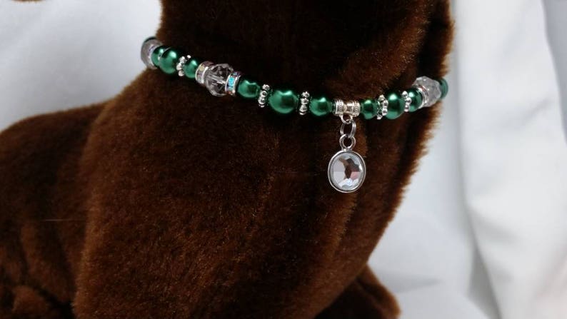 K&ouml;nnte beinhalten: Ein gr&uuml;nes und silbernes Perlenhalsband f&uuml;r Haustiere mit einem klaren Kristallanh&auml;nger.