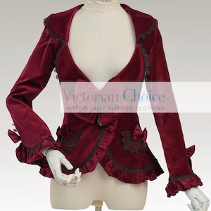 May include: A burgundy velvet jacket with black lace trim and ruffled edges. The jacket features long sleeves, decorative bows, and the text "Victorian Choice Historically Inspired Clothing". The jacket is displayed on a mannequin.