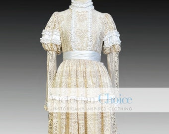 Puede incluir: Un vestido largo de encaje blanco con cuello alto, mangas largas y una faja de satén. El vestido tiene una falda de capas con volantes en el dobladillo.