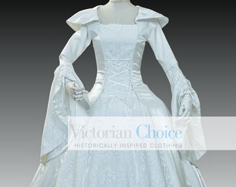 May include: A white Victorian-style wedding dress with a lace overlay and a long, flowing skirt. The dress has a square neckline and long sleeves with lace cuffs. The dress is on a mannequin and the text "Victorian Choice Historically Inspired Clothing" is visible at the bottom of the image.