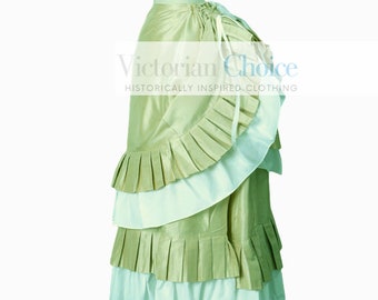 May include: A green and white layered skirt with a bustle. The skirt is made of a silky fabric and has a ruffled trim. The skirt is on a mannequin and the text "Victorian Choice Historically Inspired Clothing" is visible at the bottom of the image.