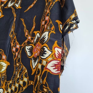 May include: Black fabric with a floral pattern in shades of orange, yellow, white, and red. The fabric has a batik style design.