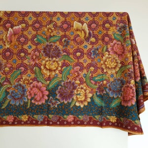 Peut inclure: Un tissu coloré avec un motif floral dans des tons de rouge, orange, jaune, vert et violet. Le tissu a un motif répétitif de fleurs et de feuilles sur un fond foncé.
