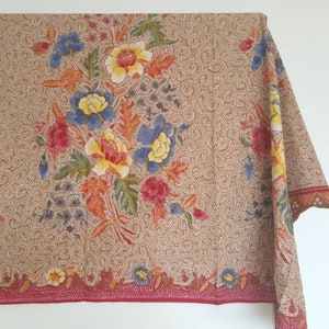 Peut inclure: Un tissu brun avec un motif floral. Le tissu présente un grand motif floral avec des fleurs rouges, jaunes, bleues et vertes. Le tissu a une bordure rouge avec un petit motif floral.