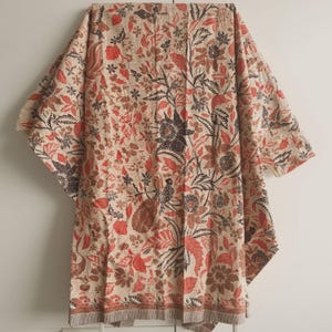 May include: A beige fabric with a floral pattern in shades of red, brown, and black. The fabric has a traditional Indonesian batik design.