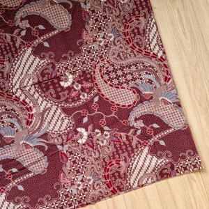 Könnte beinhalten: Nahaufnahme eines burgunderfarbenen Stoffes mit einem weißen und blauen Paisley-Muster. Der Stoff hat ein traditionelles indonesisches Batik-Design.