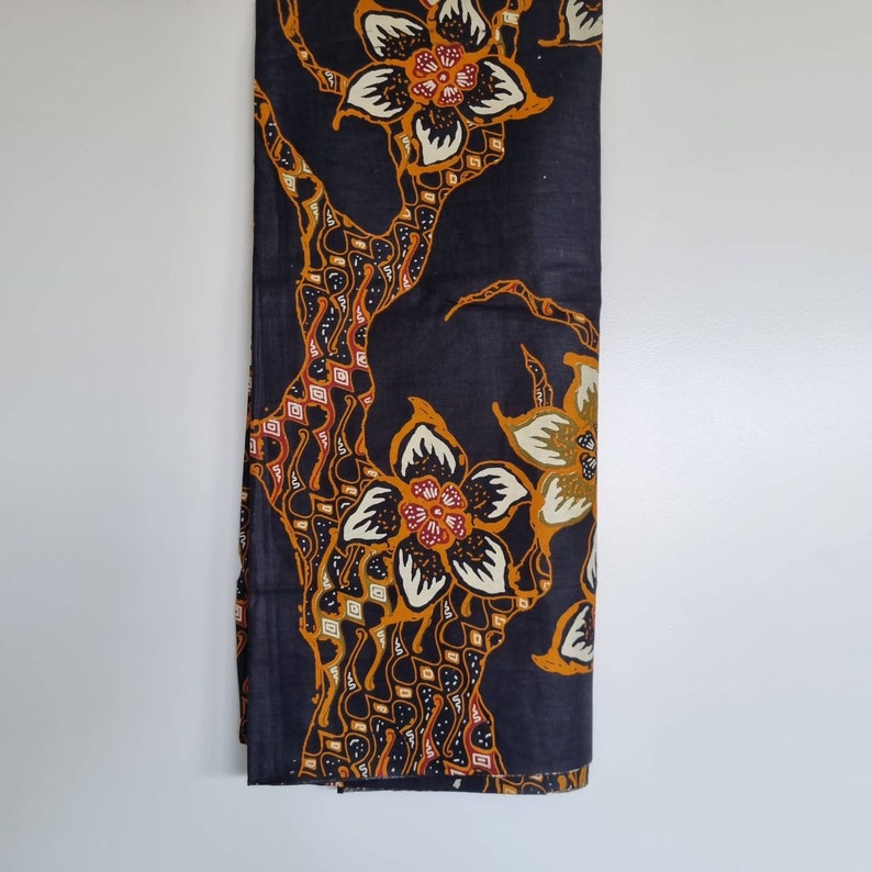 May include: Black fabric with a floral pattern in shades of orange, yellow, and white. The fabric features a repeating design of stylized flowers and leaves.