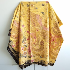 Könnte beinhalten: Ein gelber Stoff mit schwarzem Rand und einem Muster eines Phönix mit roten und goldenen Akzenten.