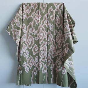 Könnte beinhalten: Olivgrüner Stoff mit einem sich wiederholenden Muster aus rosa und weißen wolkenartigen Formen. Der Stoff ist drapiert und zeigt das Design und die Textur. Die Kanten sind mit einem weißen Rand versehen.