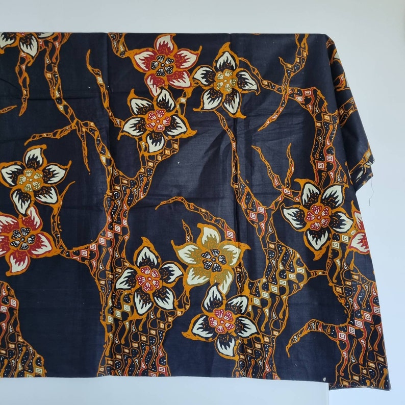 May include: Black fabric with a floral pattern in shades of orange, yellow, and red. The fabric features a repeating design of stylized flowers and branches.