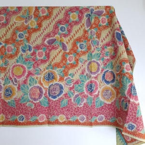 Peut inclure: Un tissu coloré avec un motif floral dans des tons de rose, orange, jaune et vert. Le tissu a un motif répétitif de fleurs et de feuilles.