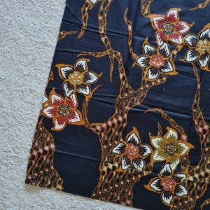 May include: Black fabric with a repeating pattern of stylized flowers and branches. The flowers are in shades of red, orange, yellow, and white. The branches are brown and black.