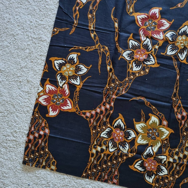 May include: Black fabric with a repeating pattern of stylized flowers and branches. The flowers are in shades of red, orange, yellow, and white. The branches are brown and black.