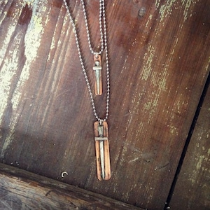 May include: Two silver chains with a copper pendant on each. The pendants are rectangular and feature a silver sword design.