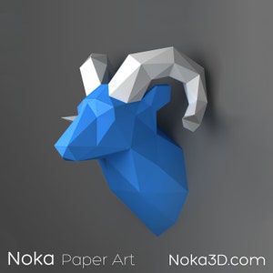 Op de afbeelding: Een blauwe en witte papieren sculptuur van een rammenkop. De sculptuur is gemaakt van gevouwen papier en heeft een 3D-effect. De rammenhoorns zijn wit en de rest van de kop is blauw.