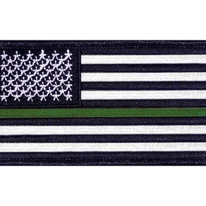 May include: An embroidered patch featuring a black and white American flag with a green stripe across the middle. The flag is surrounded by a black border.