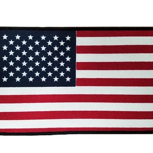 May include: A red, white, and blue American flag patch with a black border. The patch is made of fabric and has a stitched edge.