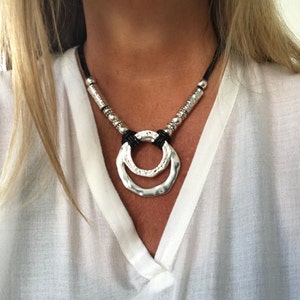 Collar de cuero para mujer con colgante de anillo en anillo y elementos metálicos plateados, collar de cuero llamativo con colgante de anillos infinitos en estilo unode50