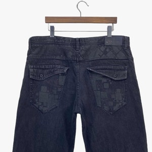 May include: Black denim jeans with a geometric pattern on the back pockets.