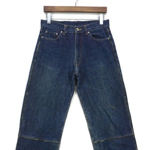 May include: A pair of dark blue denim jeans with yellow stitching along the seams. The jeans have a straight leg and a relaxed fit.