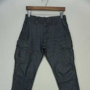 Puede incluir: Pantalón cargo gris oscuro con múltiples bolsillos y corte recto.