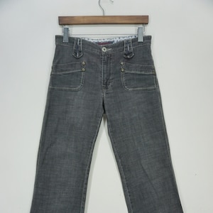 May include: Gray denim jeans with a button fly and multiple pockets. The jeans have a straight leg fit.