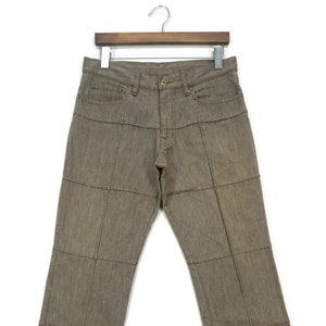 Puede incluir: Pantalón marrón a rayas con un diseño único de patchwork. El pantalón está hecho de una tela ligera y tiene un corte holgado.