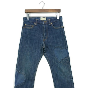 May include: A pair of blue denim jeans with heart-shaped patches on the knees.