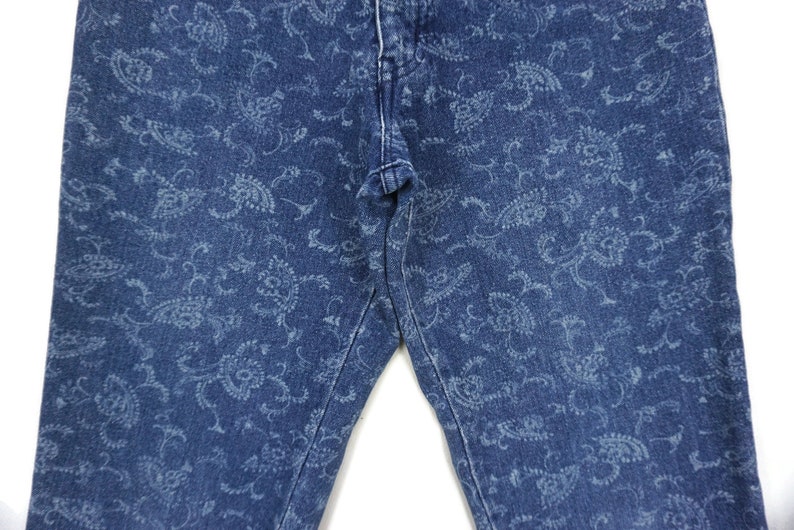 Puede incluir: Un par de pantalones vaqueros azules con un estampado paisley blanco.