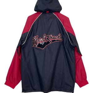Könnte beinhalten: Eine schwarze und rote Kapuzenjacke mit dem Schriftzug "Hard Knocks" in roter Stickerei auf der Rückseite.