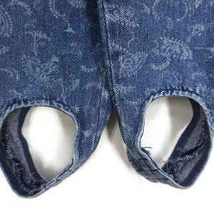 Puede incluir: Un par de pantalones vaqueros azules con un estampado floral. Los pantalones tienen un dise&ntilde;o &uacute;nico con recortes en la parte inferior.