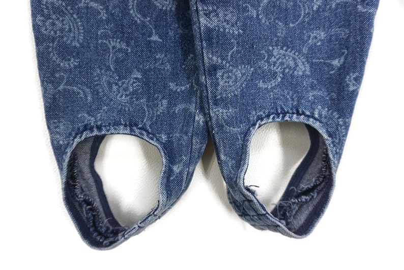 Puede incluir: Un par de pantalones vaqueros azules con un estampado floral. Los pantalones tienen un dise&ntilde;o &uacute;nico con recortes en la parte inferior.