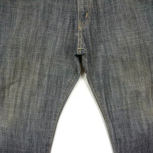 May include: A pair of dark grey denim jeans with a straight leg fit. The jeans have a subtle texture and a classic five-pocket design.