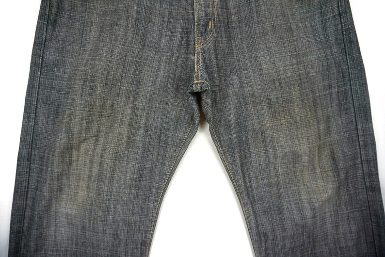 May include: A pair of dark grey denim jeans with a straight leg fit. The jeans have a subtle texture and a classic five-pocket design.