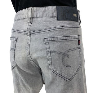 May include: Pale grey denim jeans with black stitching. They have back pockets, a leather patch with embossed text, and a small red tag. A classic style of jeans.