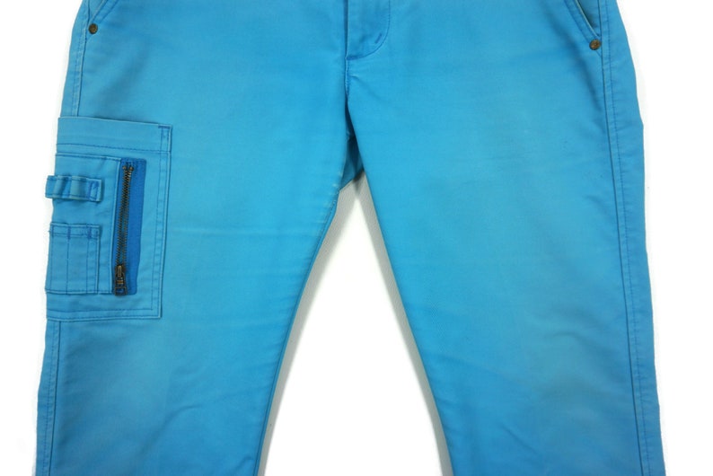 May include: A pair of blue denim trousers with a zipped cargo pocket on the left leg.
