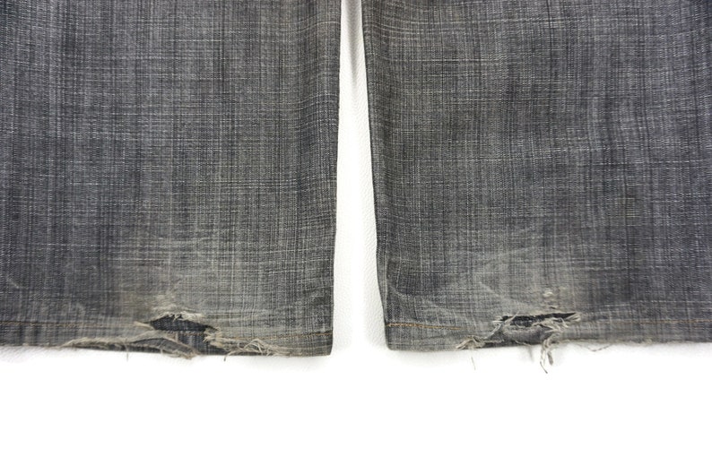 May include: A pair of dark grey denim jeans with frayed edges at the bottom.