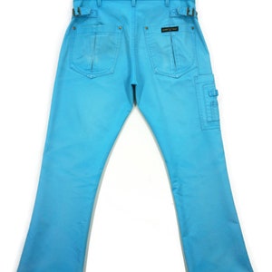 May include: A pair of light blue denim trousers with a cargo pocket on the right leg. The trousers have a belt loop detail and a small black label on the back pocket.