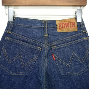 Puede incluir: Un par de pantalones vaqueros de mezclilla azul oscuro con una etiqueta roja que dice "EDWIN" y una etiqueta de talla. Los pantalones tienen dos bolsillos traseros con una distintiva costura en forma de W.