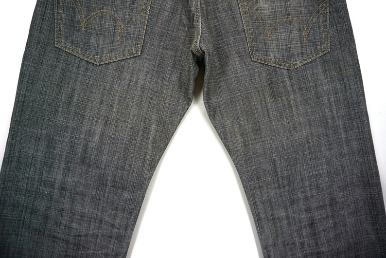 May include: A pair of dark grey denim jeans with a straight leg fit. The jeans have a classic five-pocket design with visible stitching.