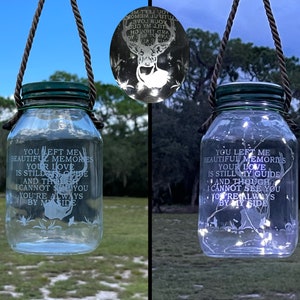 May include: Two glass jars with a rope handle and a green lid. The jars have a deer silhouette and the text "You left me beautiful memories your love is still my guide and though I cannot see you you're always by my side" etched on the glass. One jar has white lights inside.