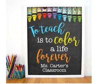 May include: A black chalkboard with white lettering that reads "To teach is to color a life forever". The chalkboard is framed in white and has a row of colorful crayons at the top. The text "Ms. Carter's Classroom" is at the bottom of the chalkboard.